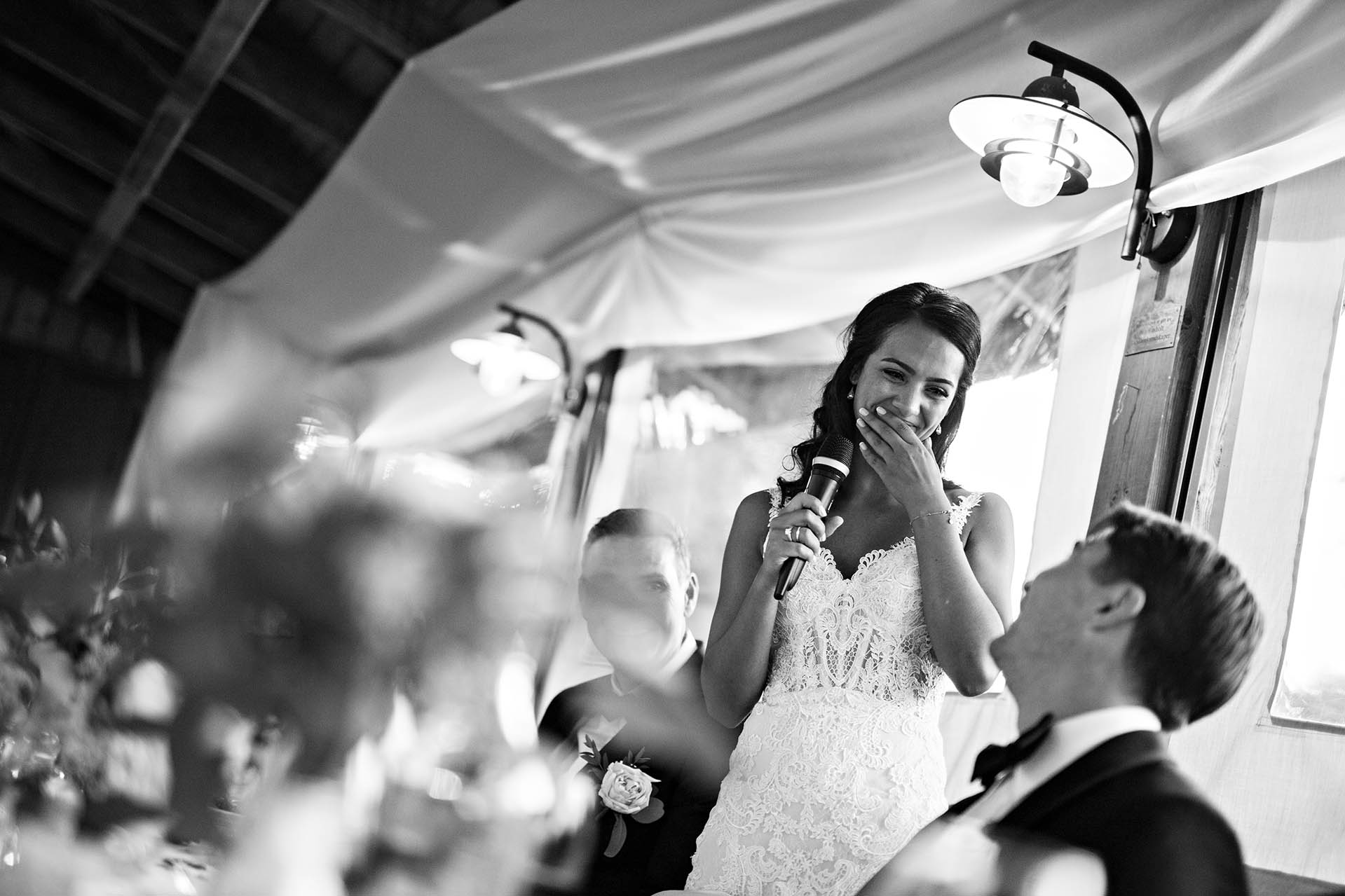 Brudens tale til brudgommen. En smilende brud med tårer i øynene som holder en mikrofon.