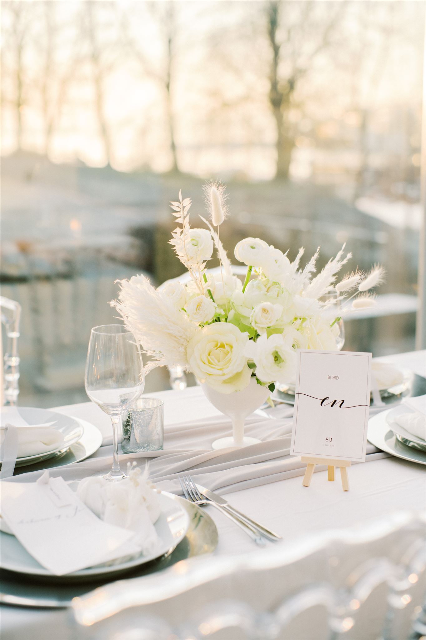 Moderne bryllupsbord med elegant bordnummer og dekketallerken i sølv.