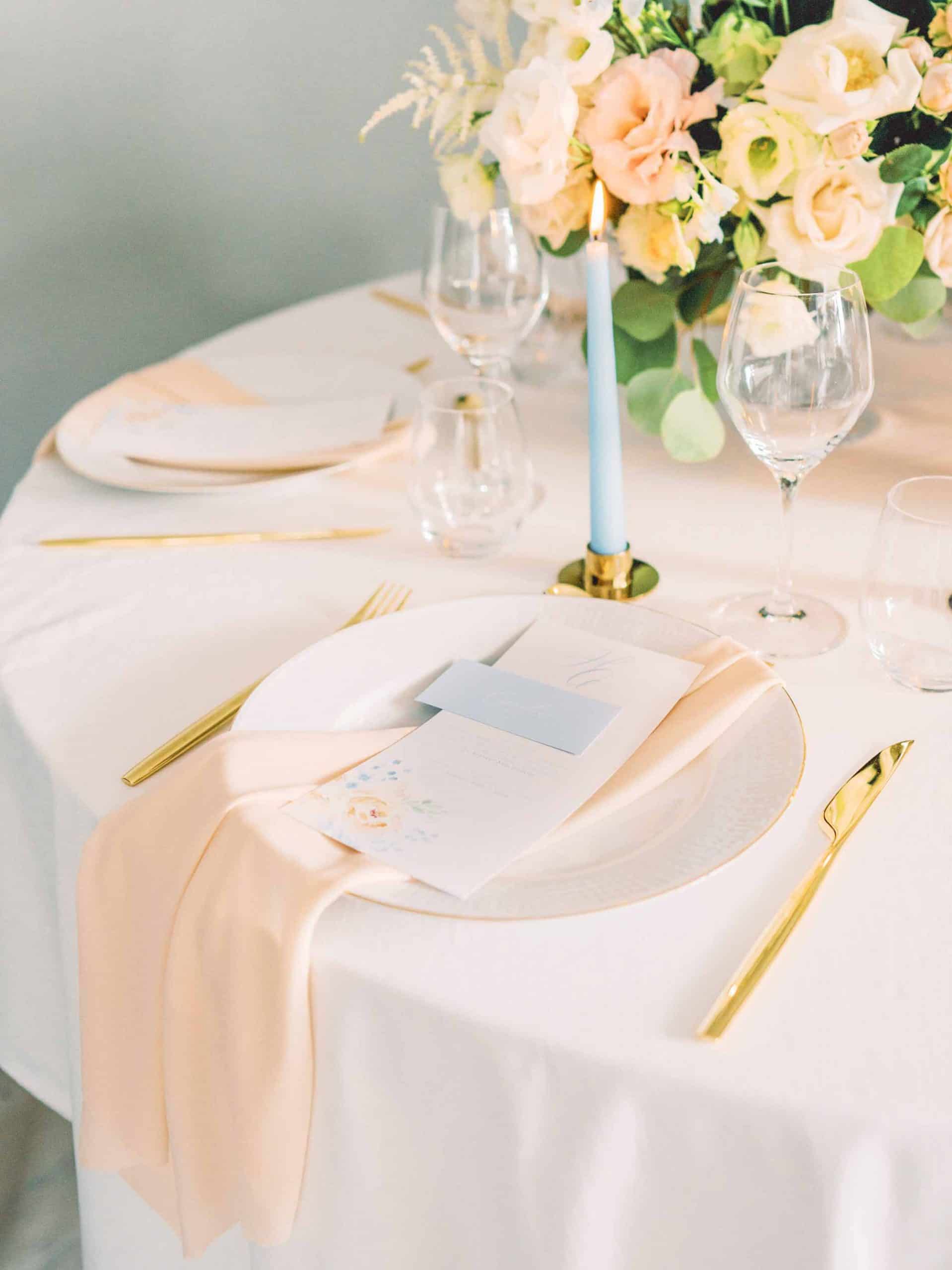 gullbestikk med fersken serviett, lyseblått bordkort og fersken blomsterbukett
