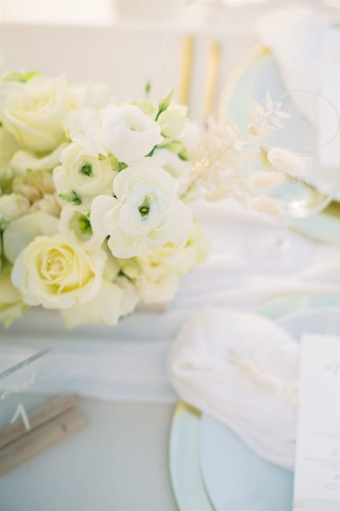 Blomsterbukett på bryllupsbord i beige med dekketallerken i gull.